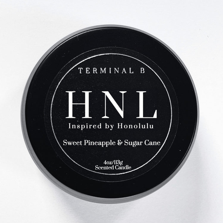 HNL 4oz Travel Tin candle by Terminal B. Sweet Pineapple and Sugar Cane fragranced and displayed against a white background. Inspired by Honolulu, Hawaii, carefully designed for an elegant, long-lasting scent.